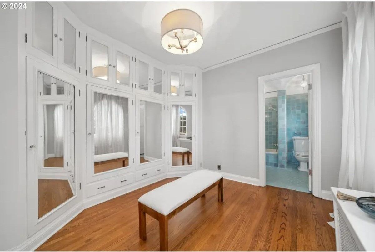 Built-in white cabinetry with mirrored panels that extend across the walls, providing ample storage and a spacious feel.