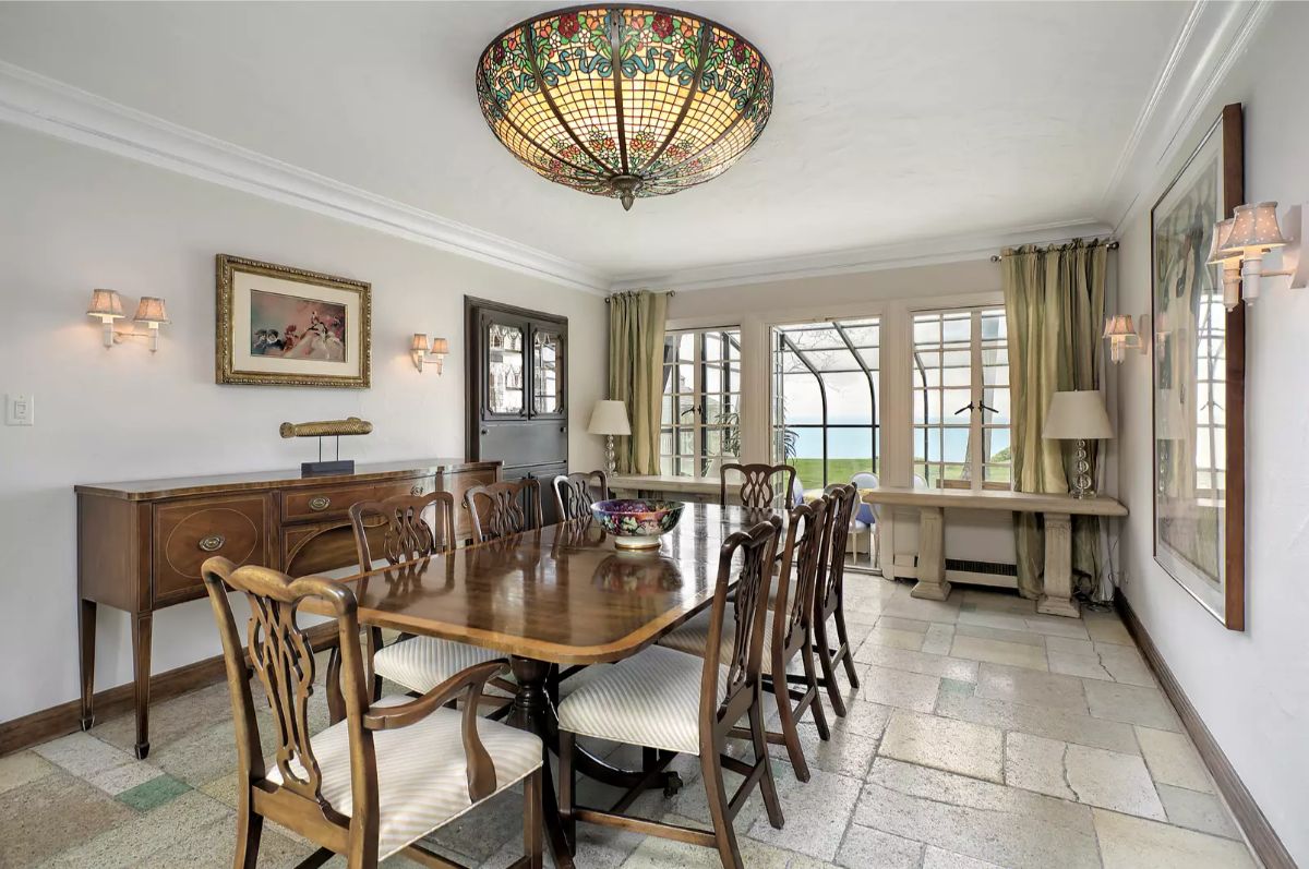 Long wooden dining table is surrounded by elegant chairs with striped upholstery.