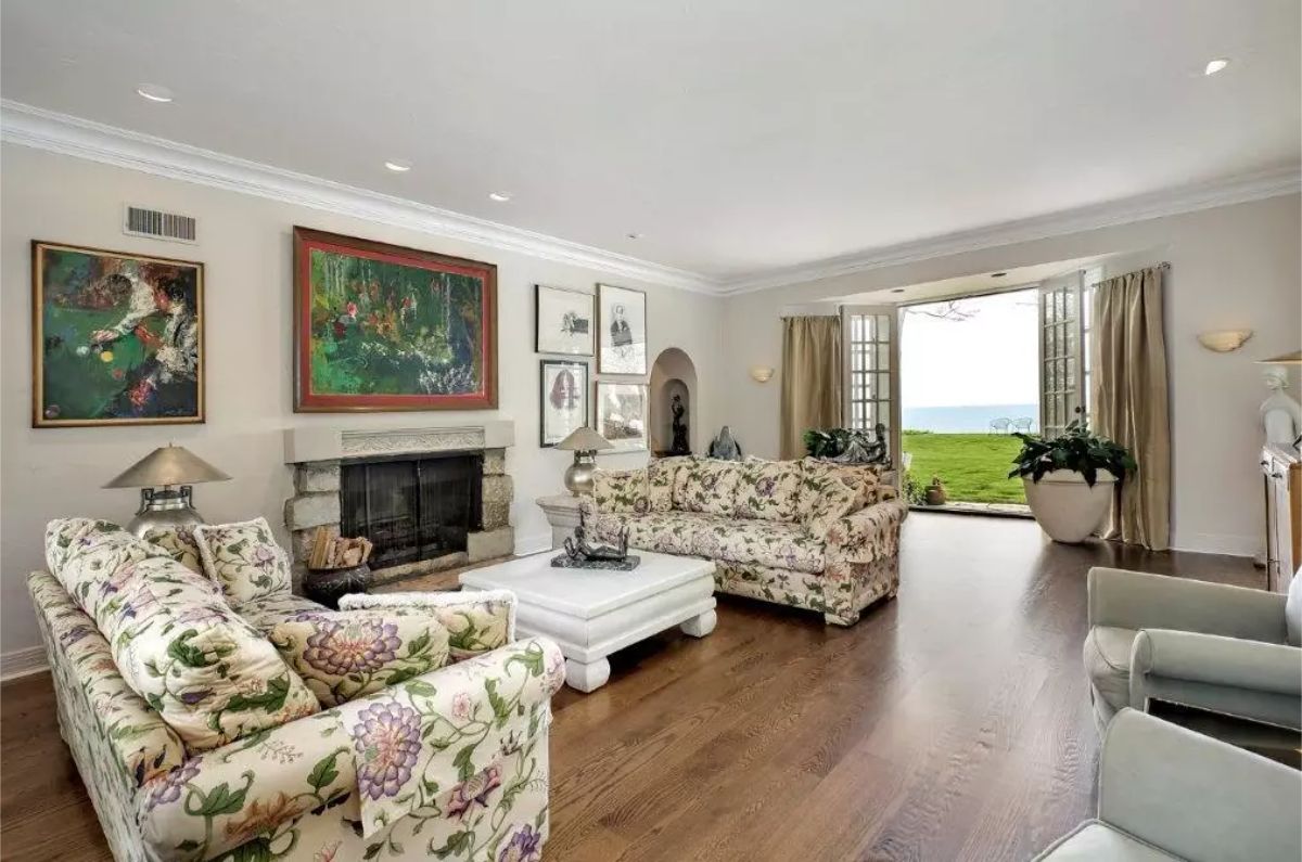 Spacious living room features floral-patterned sofas and a stone fireplace as the central focal point.