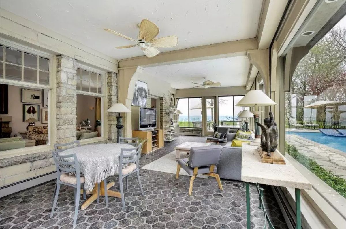 Hexagonal stone flooring and large windows that provide expansive views of the outdoor pool and lake.