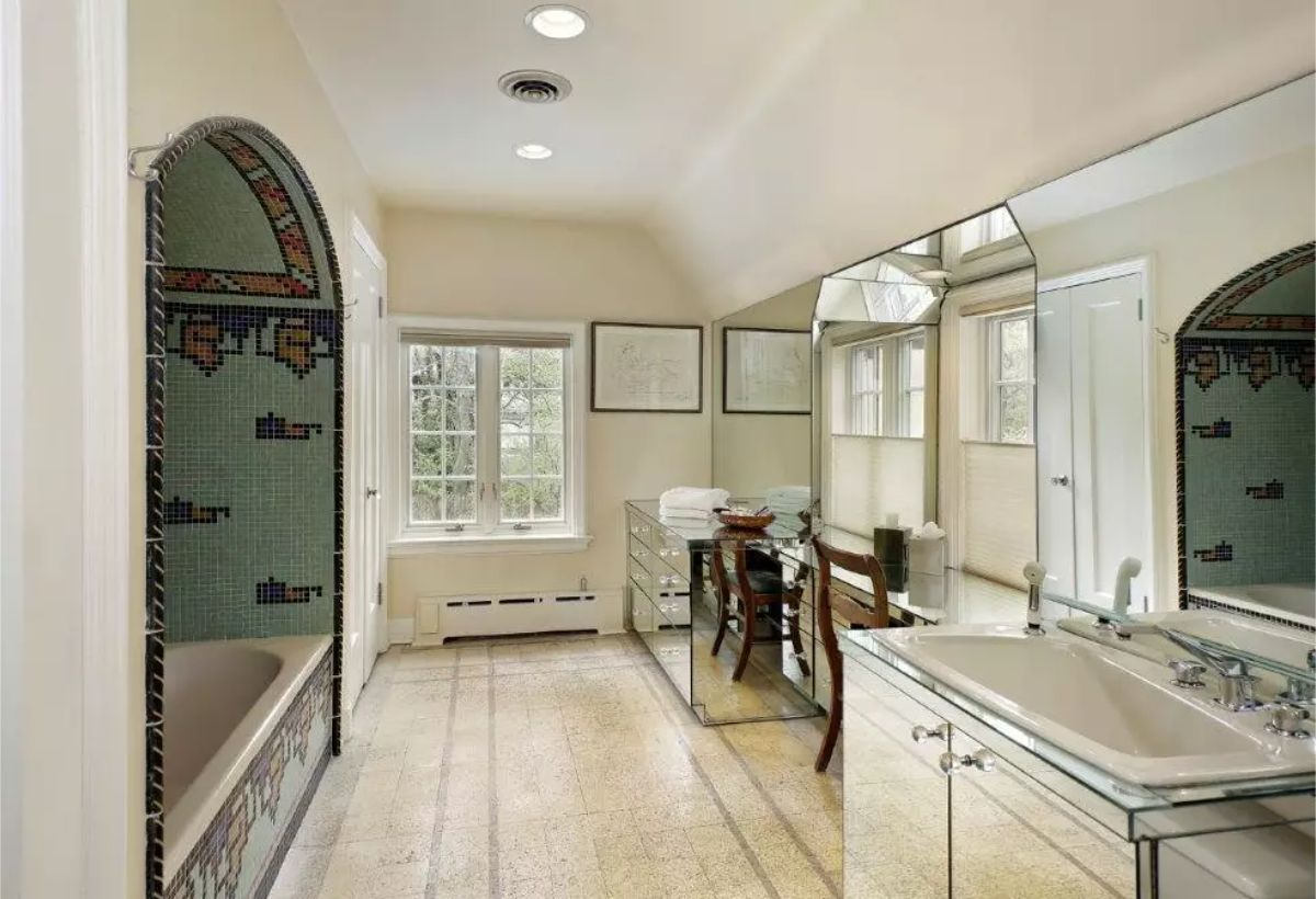 The bathroom showcases a unique tub enclosure adorned with colorful mosaic tilework and an arched design.