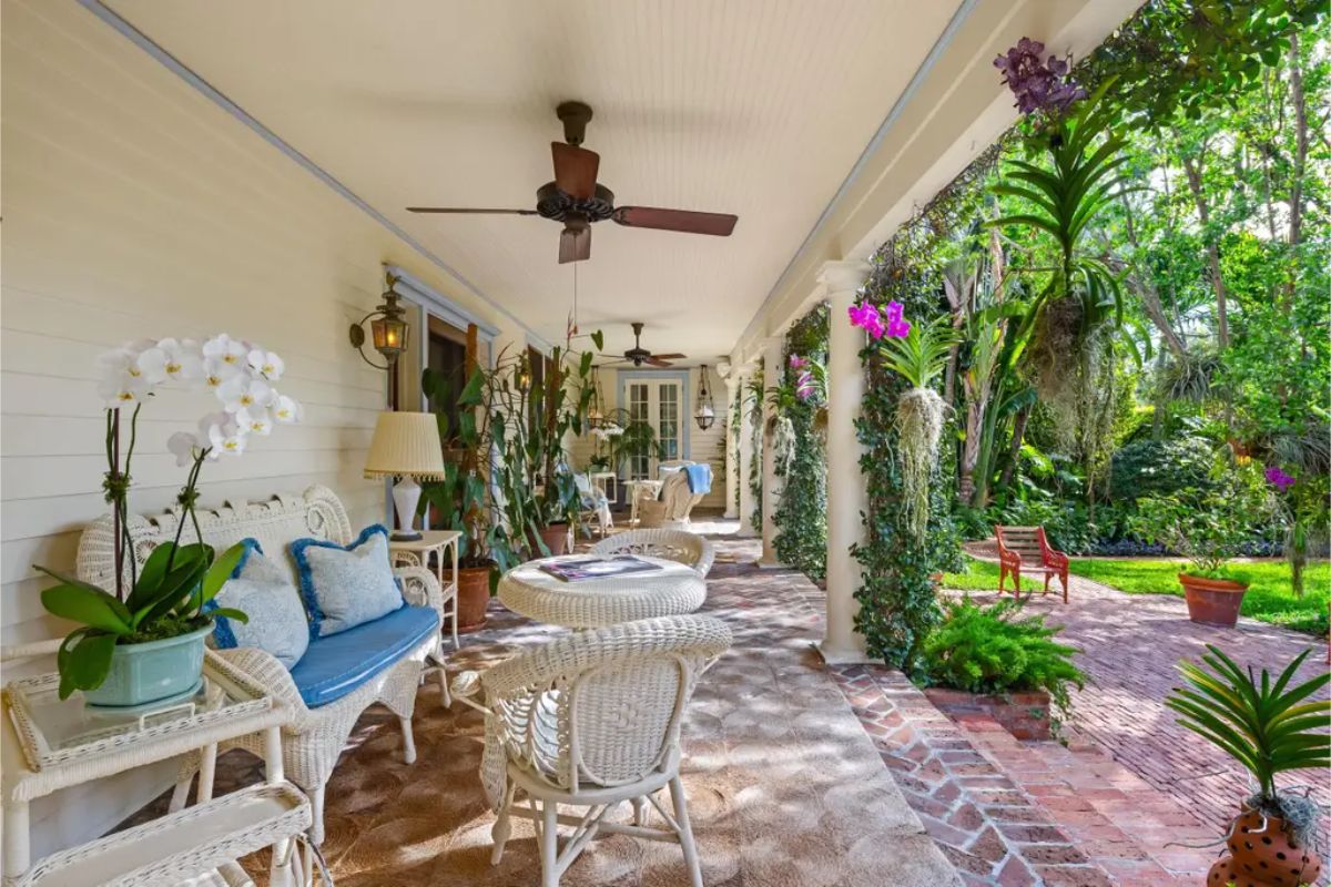 Covered veranda lined with white wicker furniture and accented by ceiling fans for added comfort.