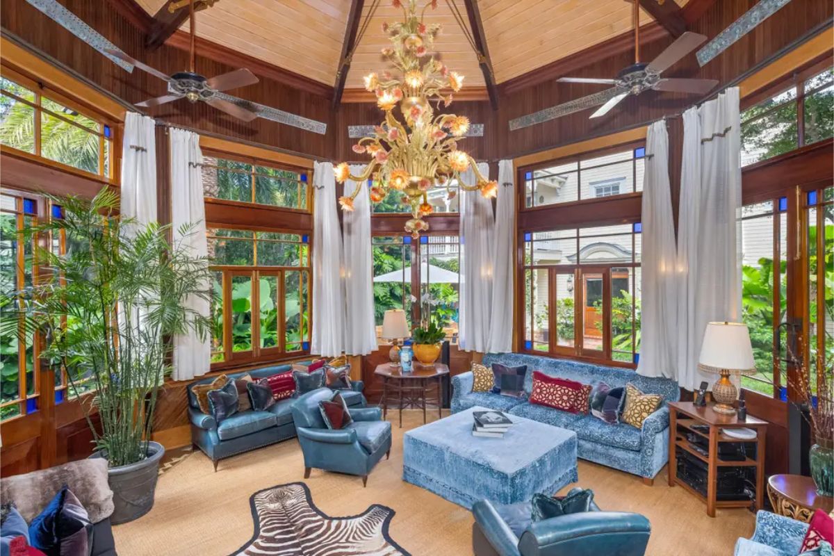 Wood-paneled sunroom with high vaulted ceilings and a central chandelier.