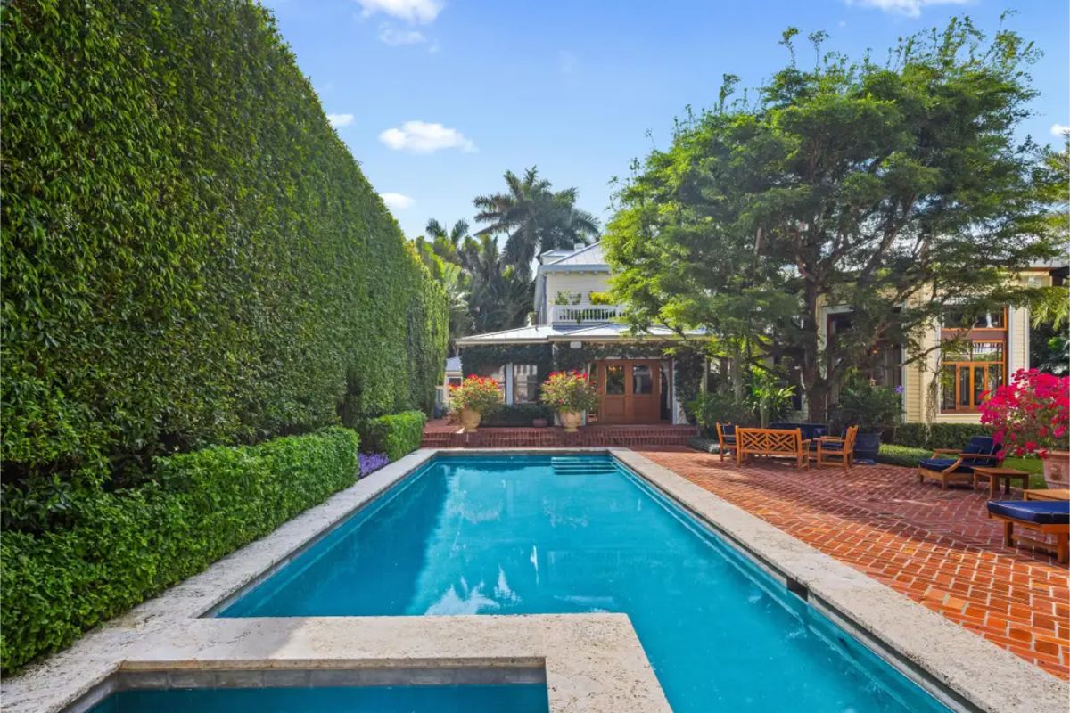 Long rectangular pool surrounded by a meticulously maintained brick patio.