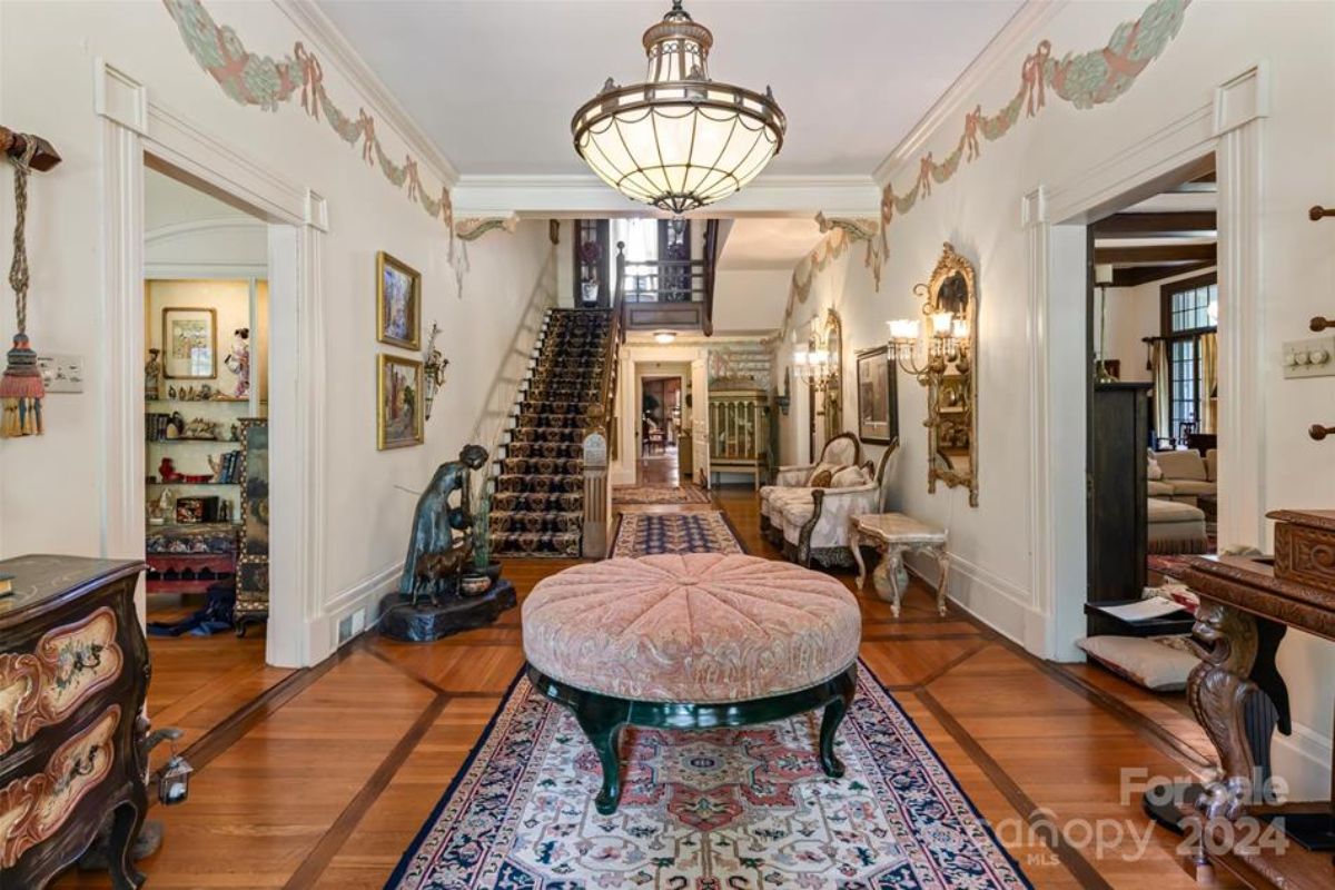 Grand entryway with intricate wood flooring and vintage decor.