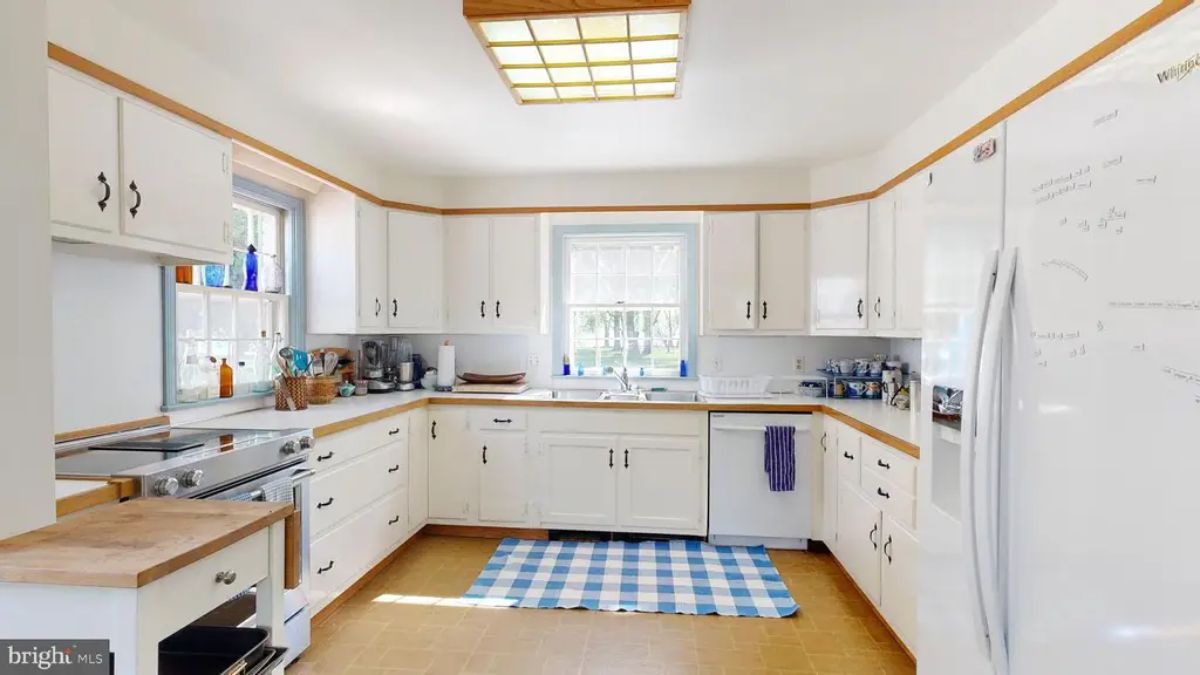 Kitchen is designed with white cabinetry and natural wood trim for a clean, classic look.