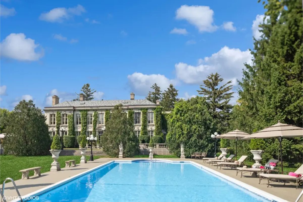 A rectangular pool with surrounding lounge chairs and umbrellas creates a serene outdoor retreat.