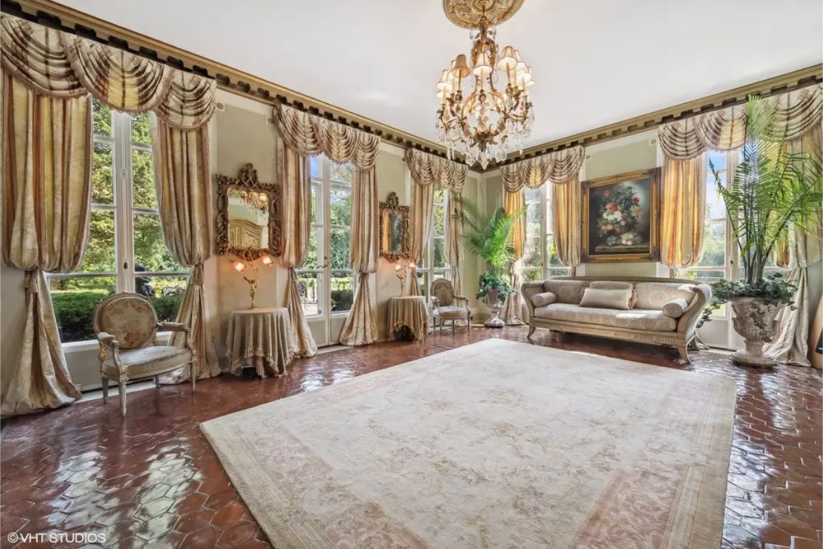 Large windows framed by opulent drapery provide abundant natural light and garden views.