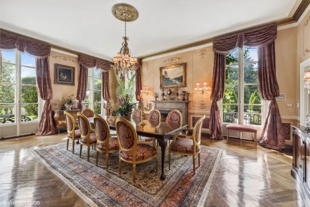 An ornate chandelier and ceiling medallion anchor the dining space, surrounded by gold-framed chairs with patterned upholstery.