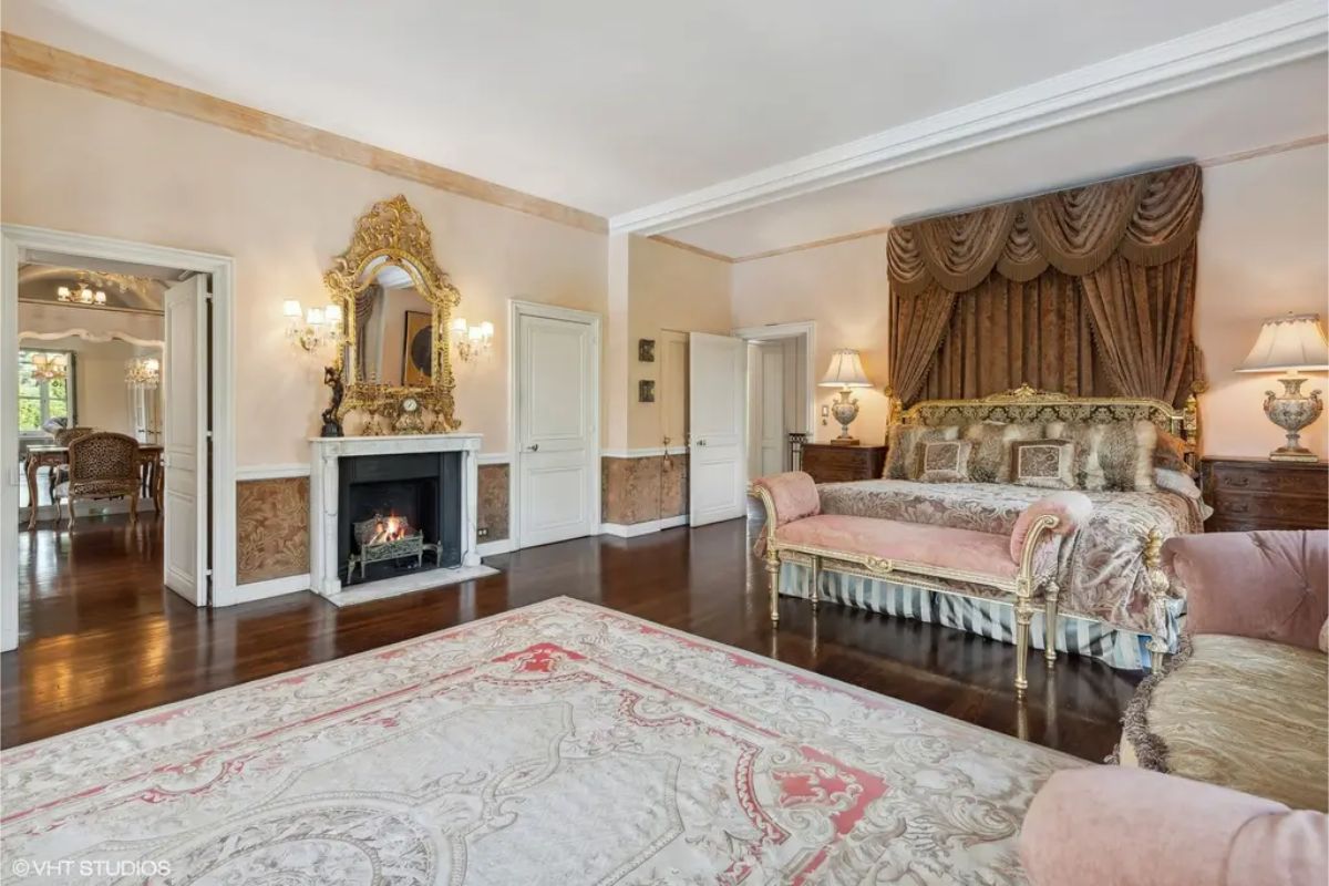 Intricately carved gold-framed mirror and matching sconces accent the marble fireplace.