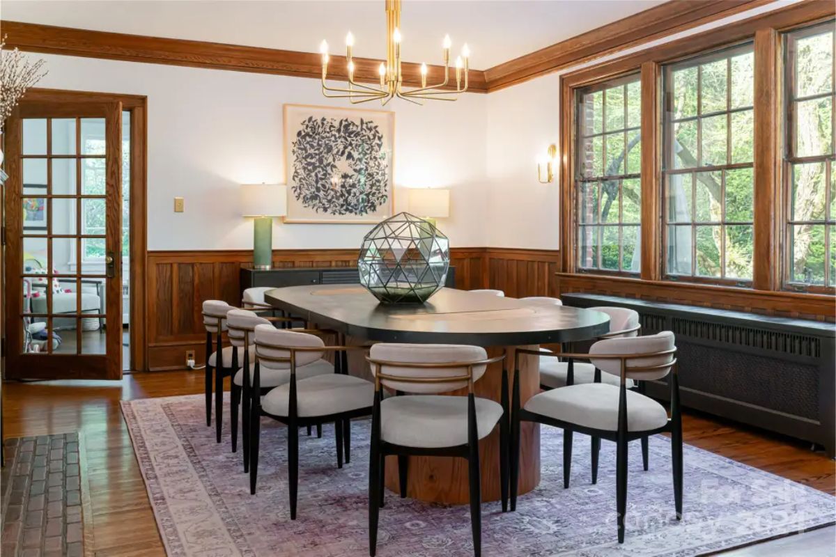 Contemporary oval table surrounded by upholstered chairs with sleek wooden frames.