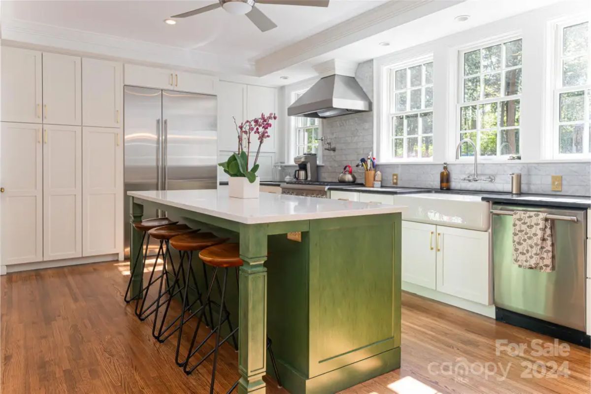 A large green island with white quartz countertop and bar seating.