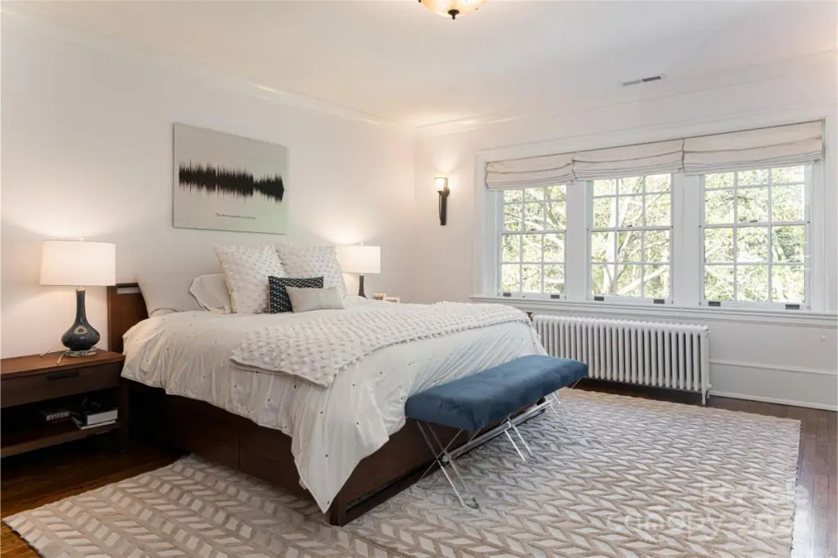 Bedroom features a comfortable bed with layered white bedding and decorative pillows.