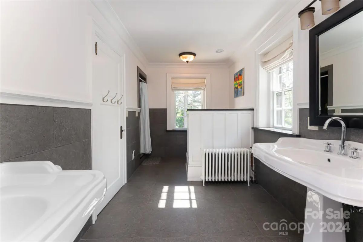 Combines dark floor tiles and wainscoting with white walls for a balanced, clean aesthetic.