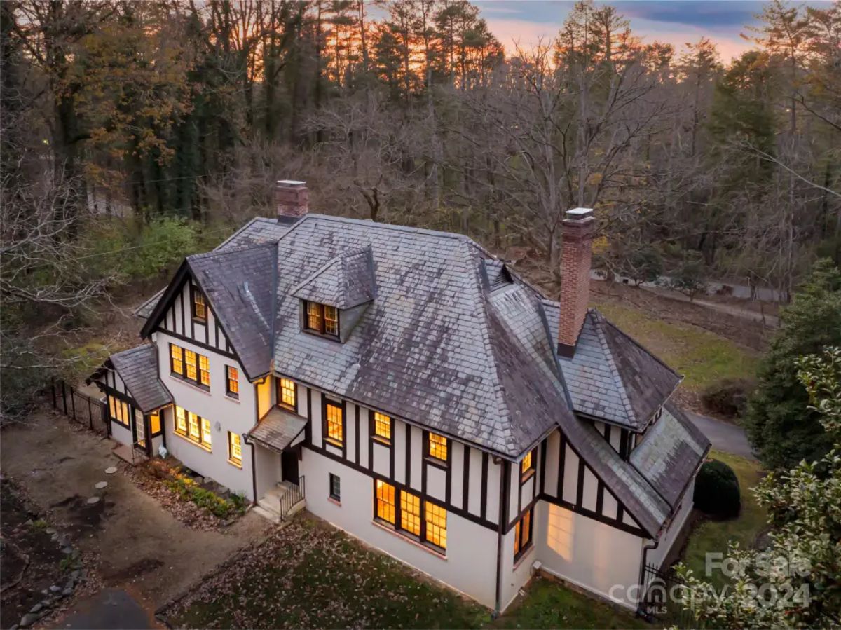 Tudor-style home features a steeply pitched slate roof, decorative half-timbering, and multiple chimneys.