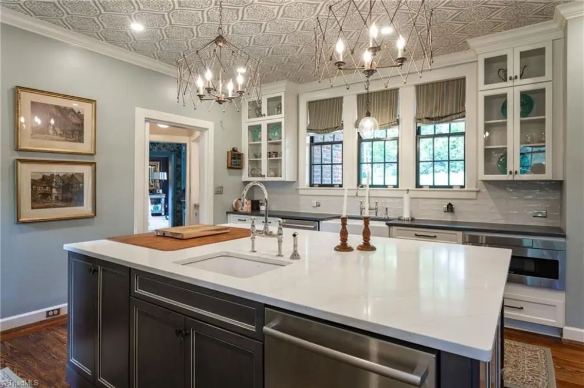 A large island with a white countertop and dark cabinetry.