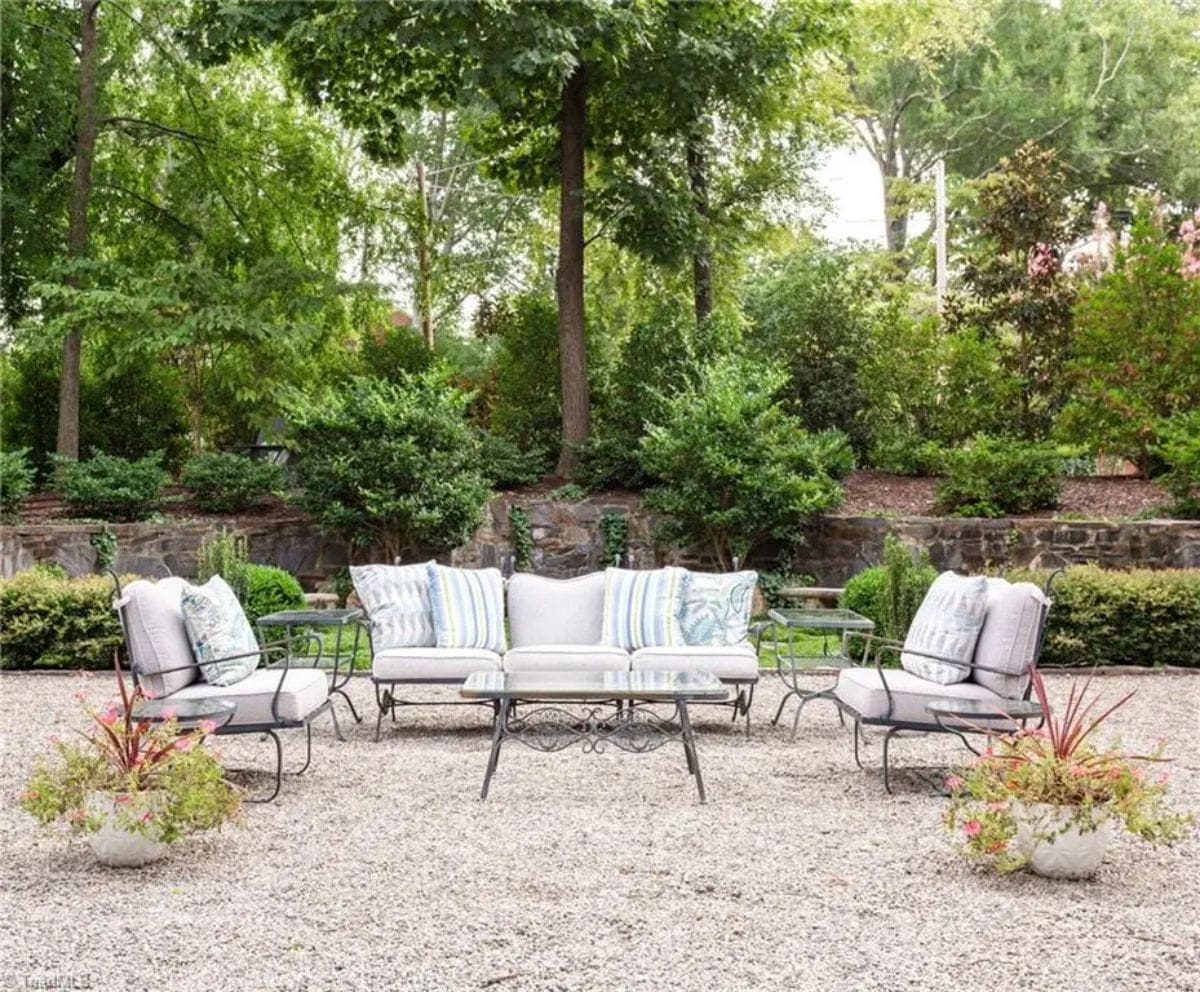 Patio area features wrought iron furniture with cushioned seating, styled with striped and floral throw pillows.