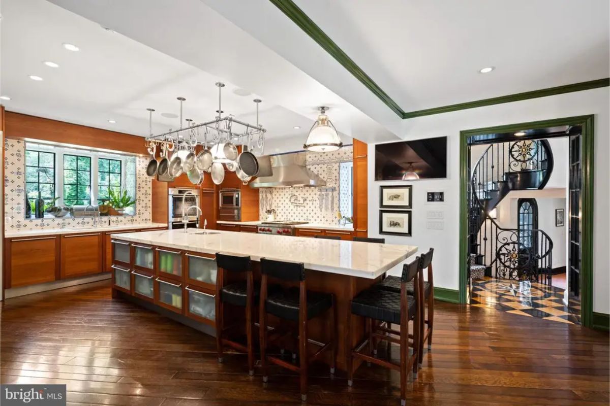 Kitchen with a central island, marble countertops, and a pot rack suspended above for convenience.