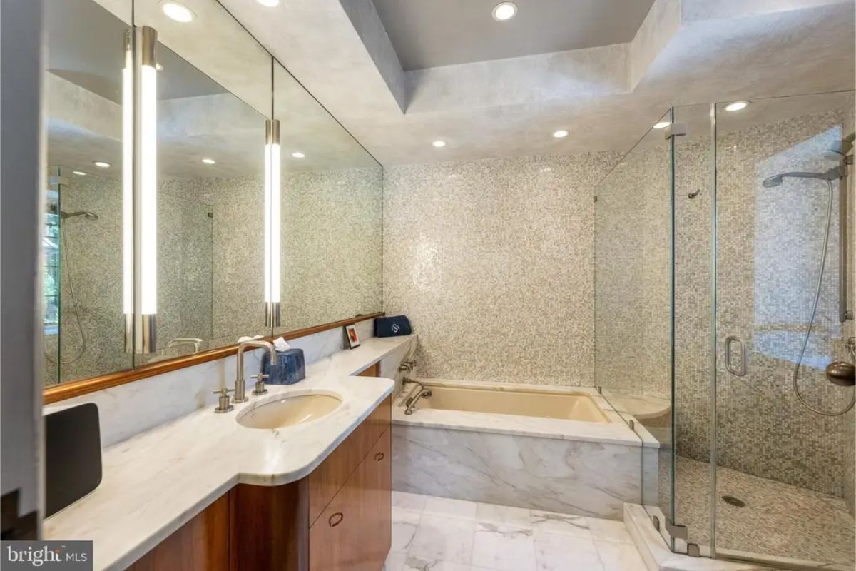 Contemporary bathroom includes a glass-enclosed shower and a soaking tub surrounded by marble accents.