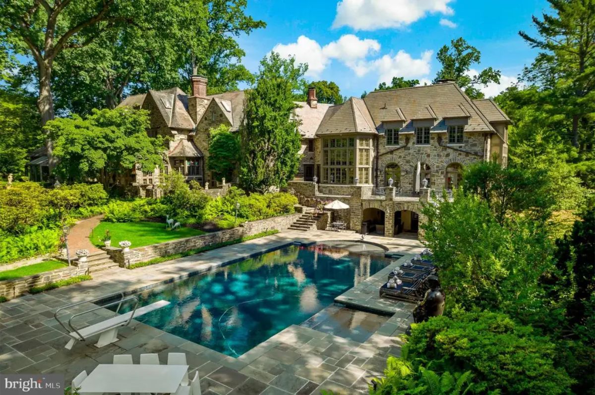 Stone manor set on lush landscaped grounds includes a large swimming pool and surrounding patio for outdoor enjoyment.