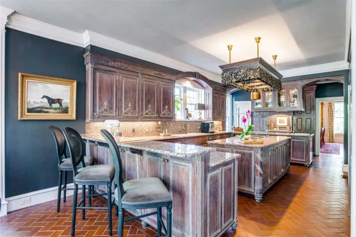 Kitchen with dark-stained, ornate cabinetry and granite countertops throughout.