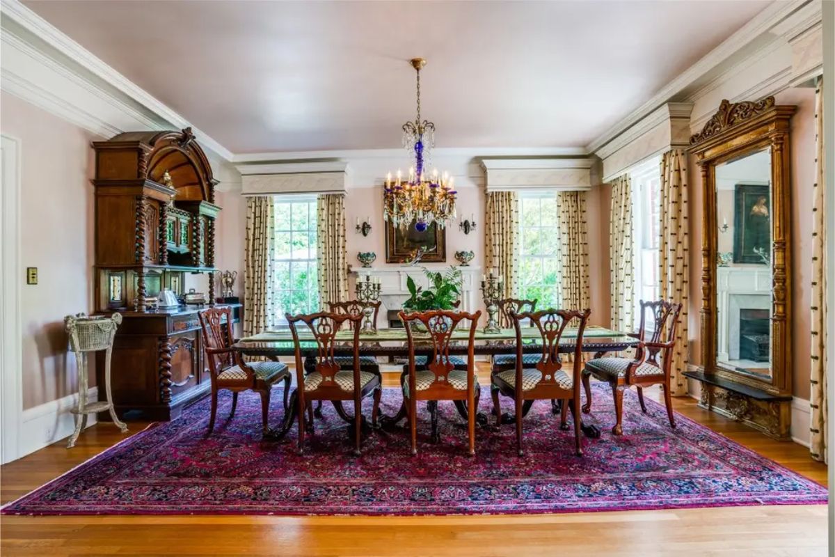 Dining room centered around a long table with carved wooden chairs.