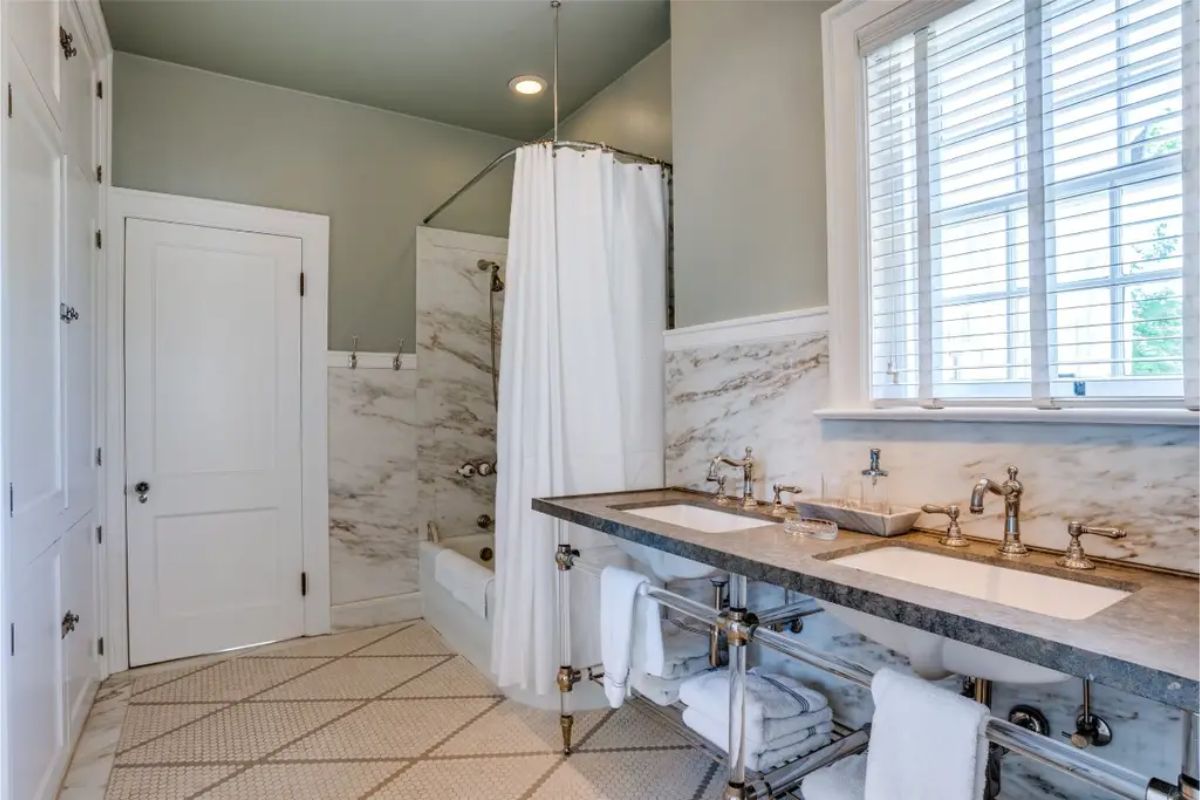 Bathroom with dual sinks set in a marble countertop and polished metal fixtures.