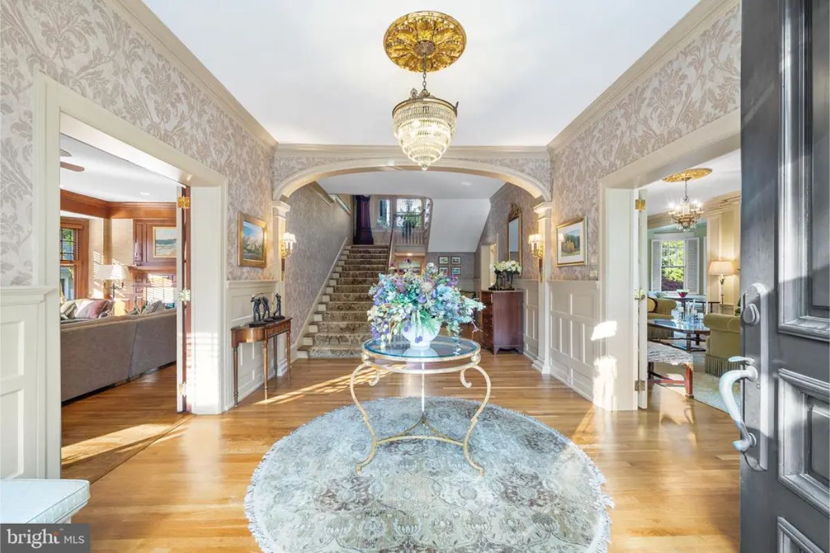 A spacious foyer with hardwood flooring and detailed wainscoting on the walls.