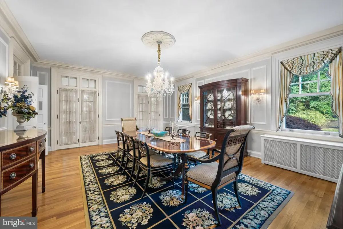 A long rectangular table surrounded by upholstered chairs with carved wooden frames.