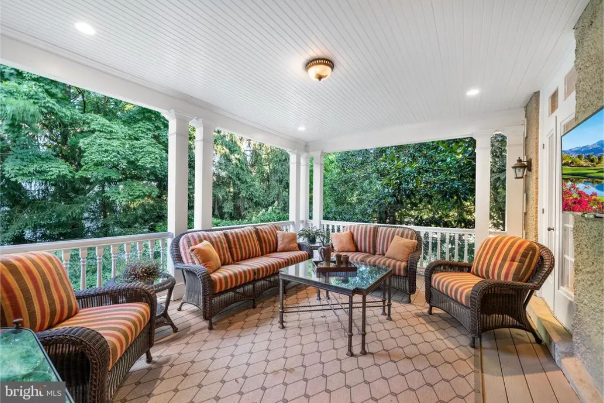 Outdoor space includes a covered porch surrounded by white railings and columns