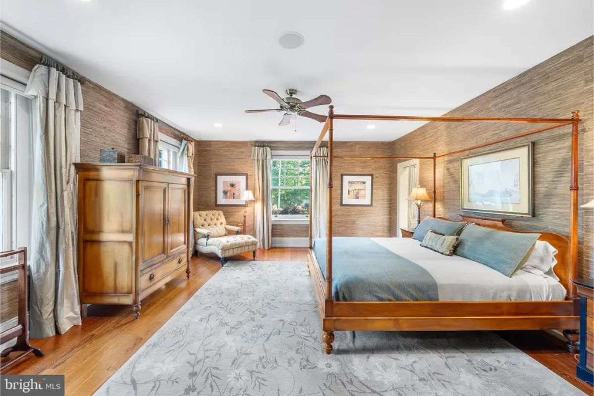 Four-poster bed with light bedding and matching wooden furniture, including a wardrobe.