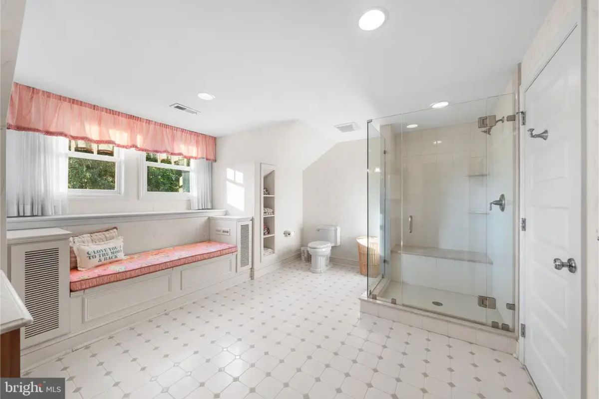 A glass-enclosed walk-in shower with modern fixtures and a tiled bench.