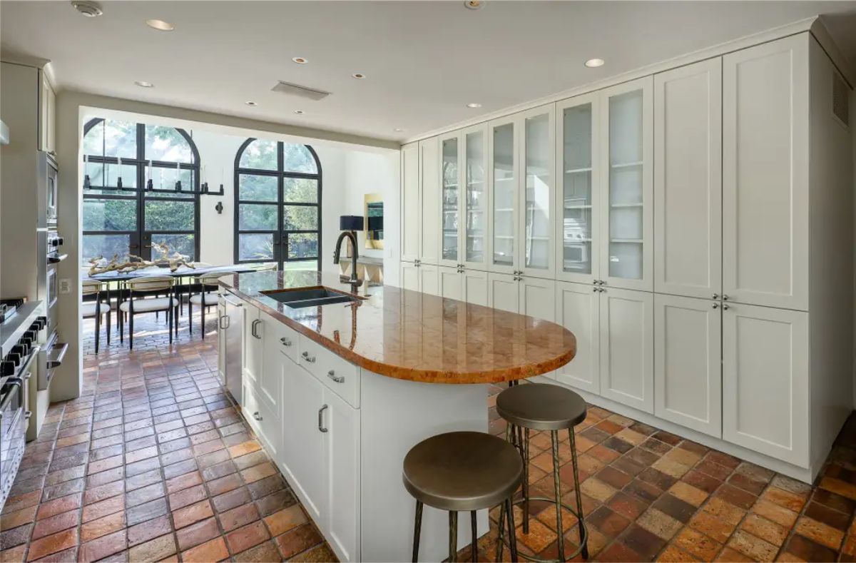 Kitchen with white cabinetry and a terracotta tile floor.