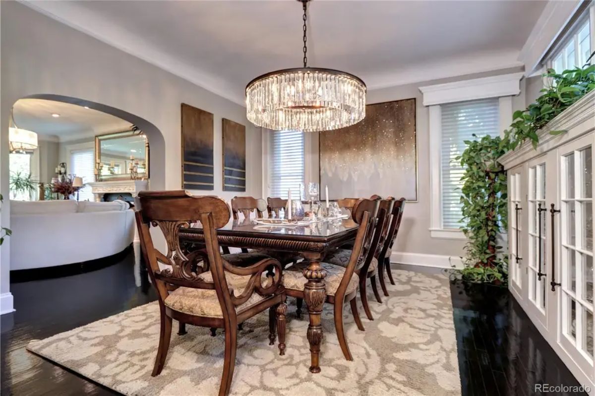 A grand wooden dining set complemented by a sparkling crystal chandelier.