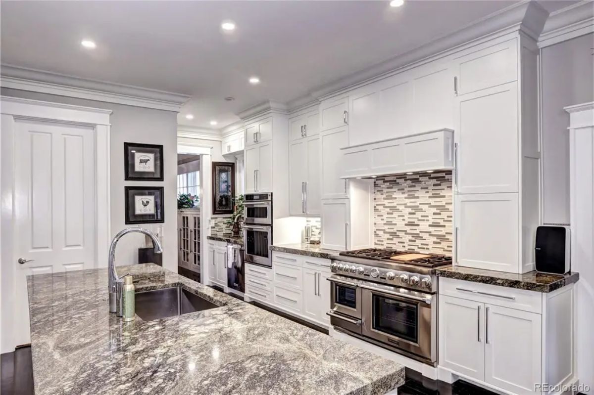 White cabinetry, granite countertops, and a striking mosaic tile backsplash.