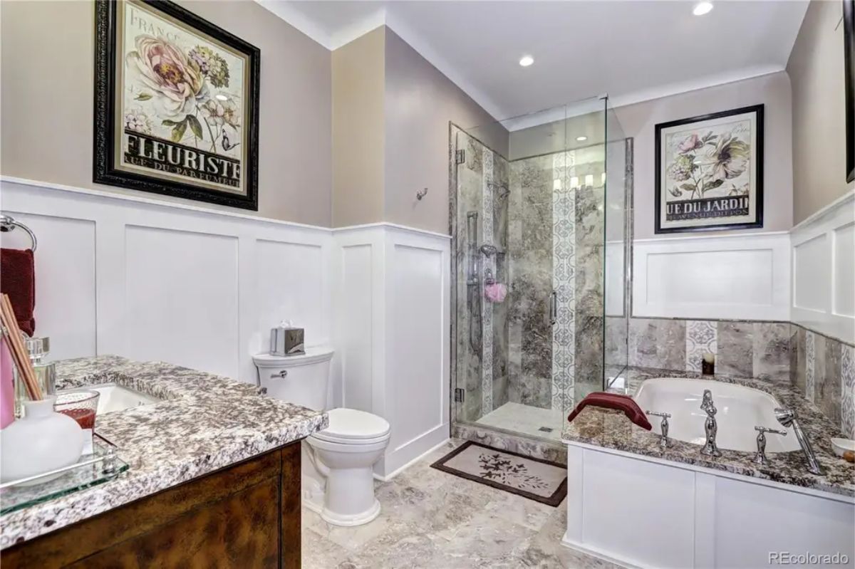 Walk-in glass-enclosed shower with intricate tile detailing and a soaking tub surrounded by granite accents for a luxurious spa experience.