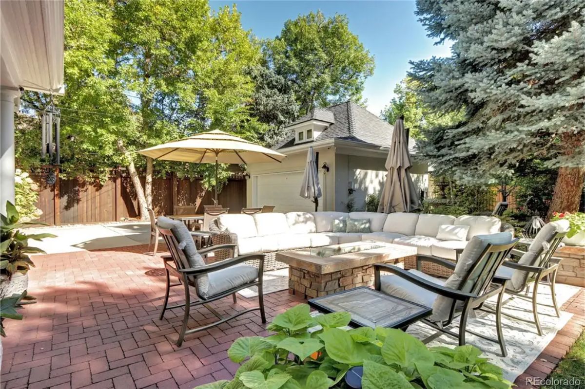 This inviting backyard features a spacious brick patio surrounded by mature trees, offering privacy and tranquility.