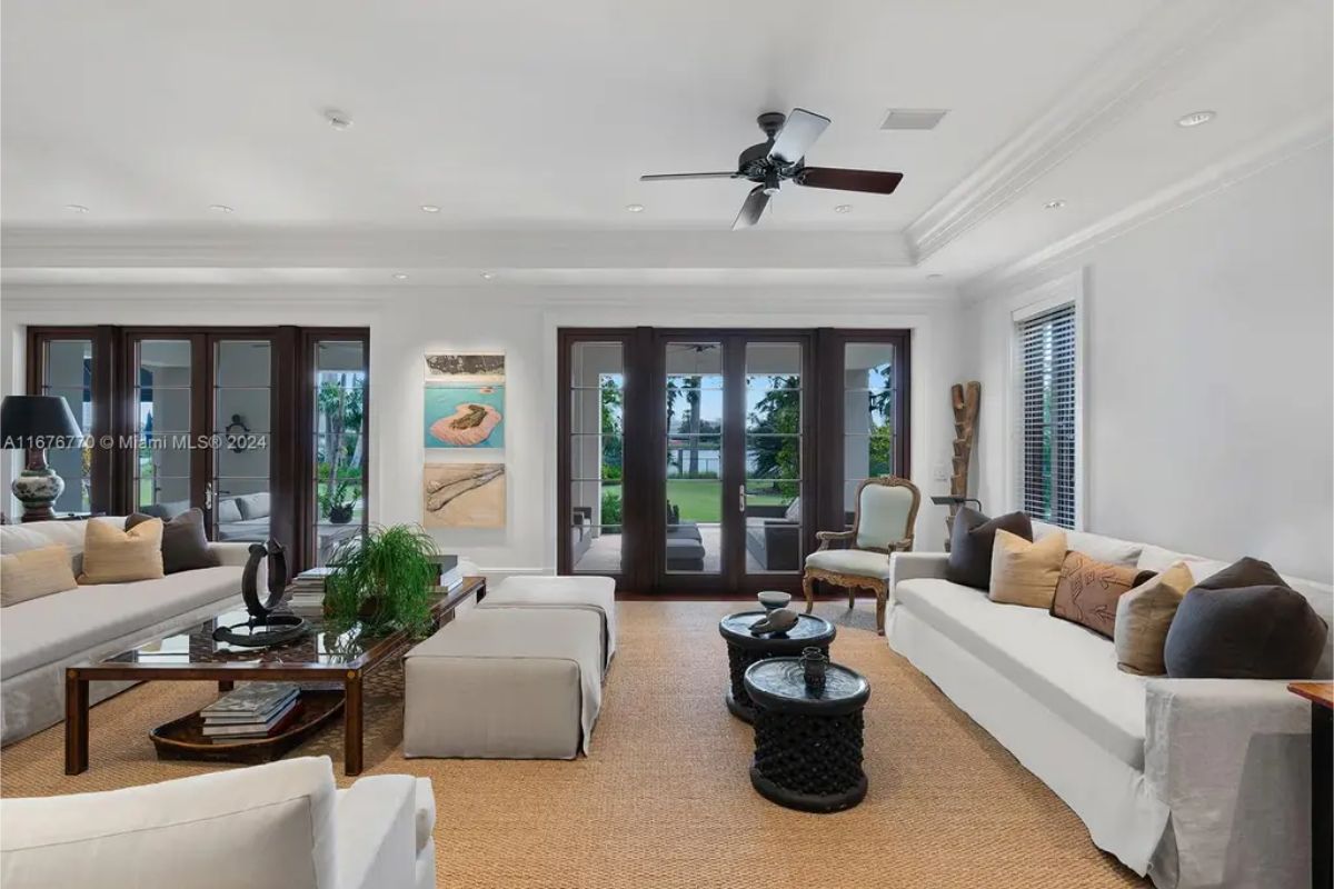 Living room with white walls and a neutral color palette, accented by dark wood French doors.