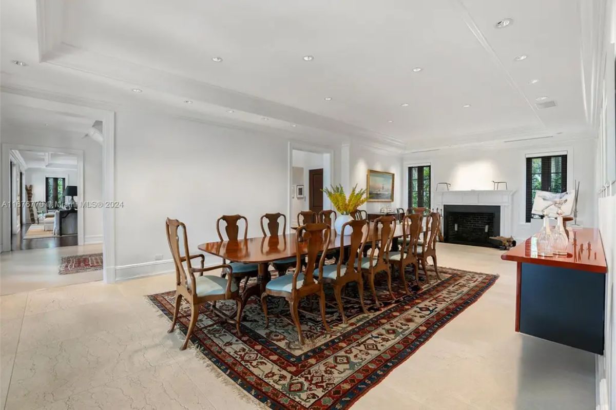 Large dining room featuring a polished wood table with matching chairs set on a patterned area rug.