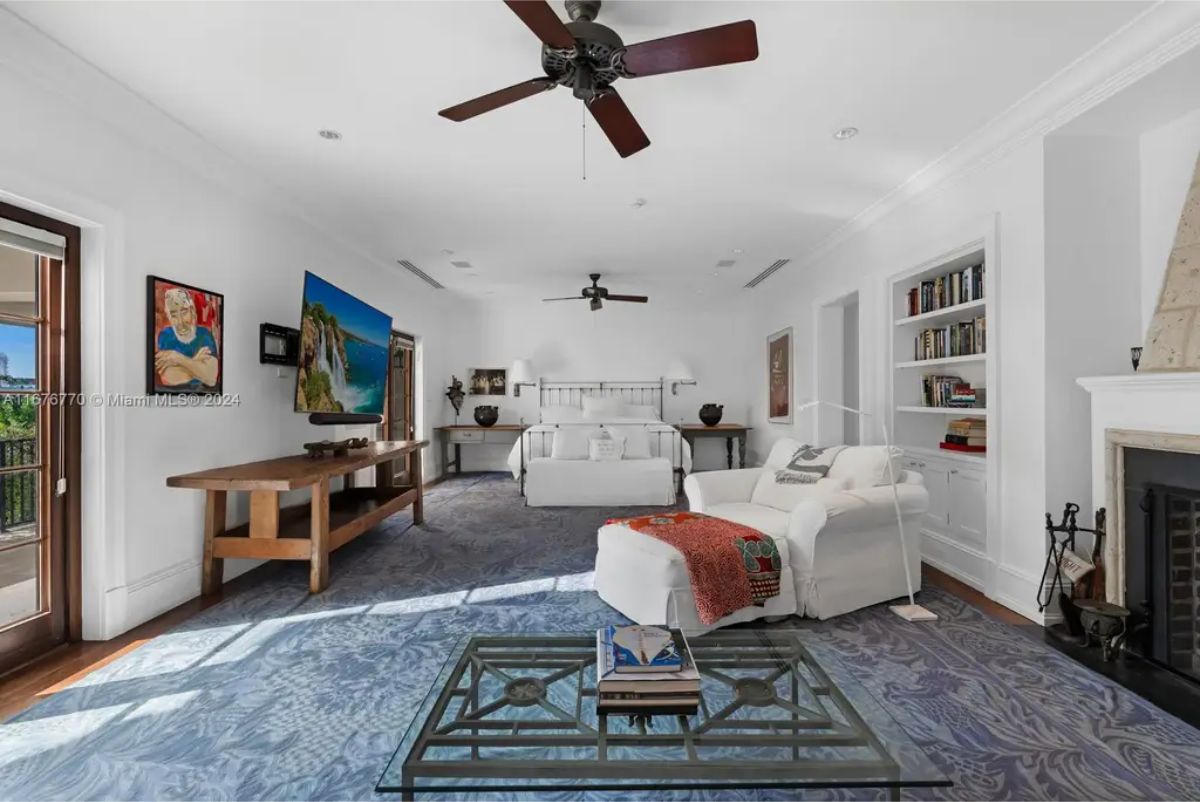 Expansive master bedroom featuring a king-size bed, built-in bookshelves, and a stone fireplace.