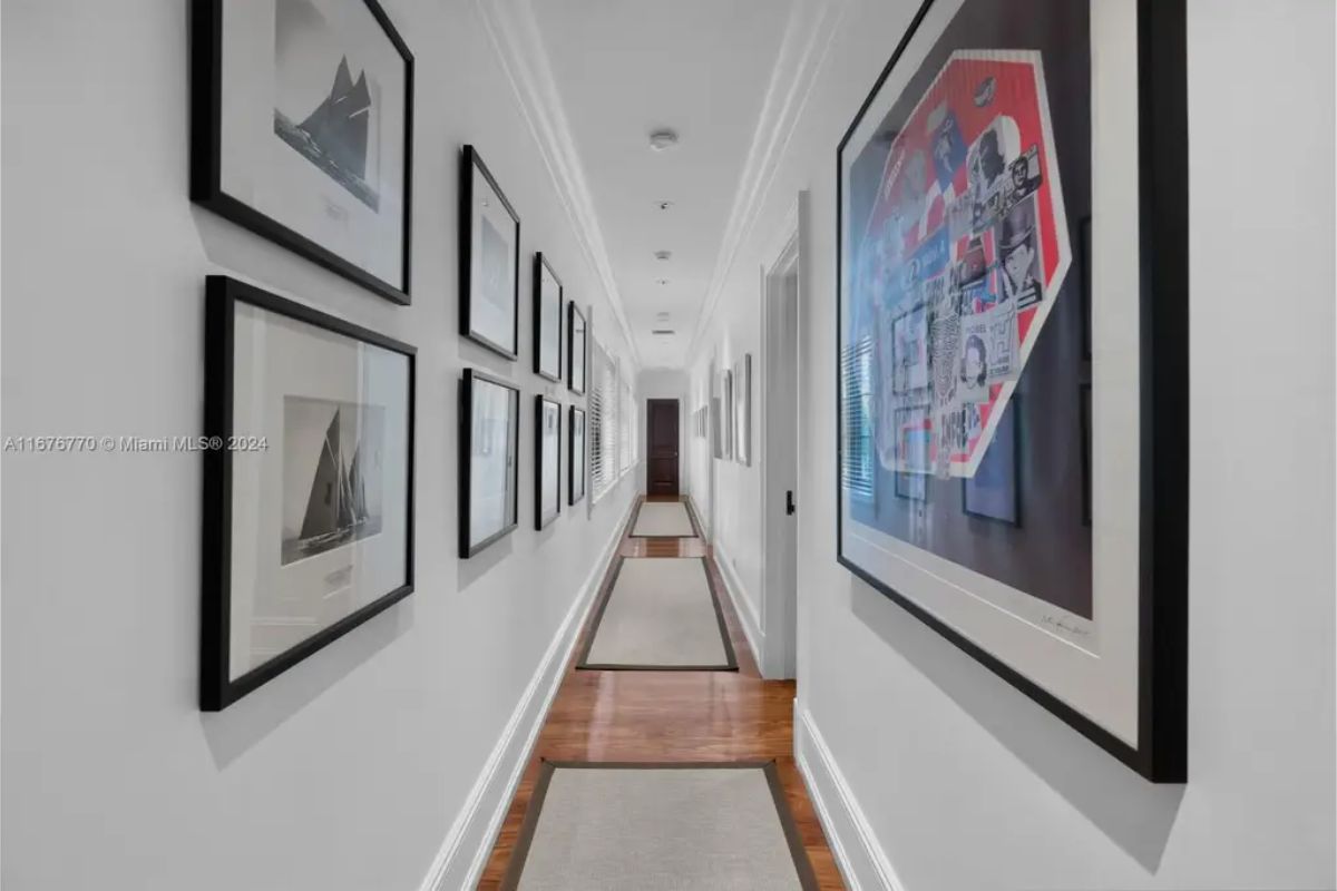 Long hallway adorned with framed artwork displayed on clean white walls.