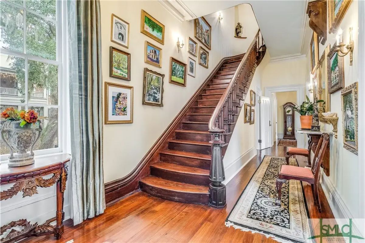 Wooden staircase with curved banister ascends to the upper level.