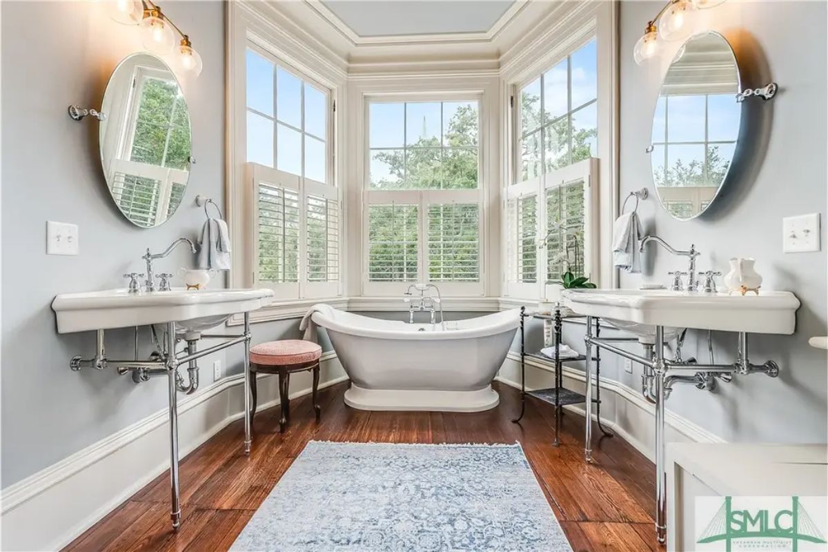 Bathroom features a centrally positioned freestanding soaking tub surrounded by large windows that provide ample natural light.