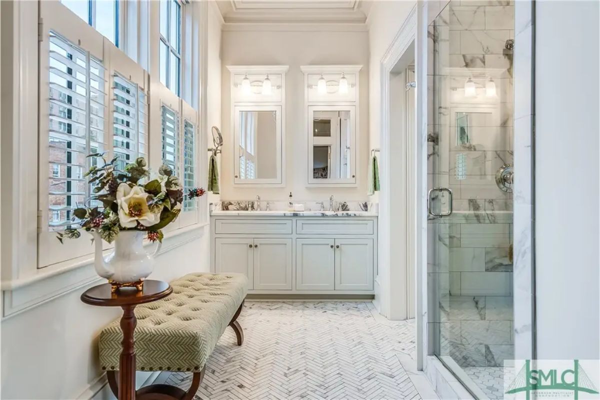 White double vanity with marble countertops and mounted mirrors creates a clean design.