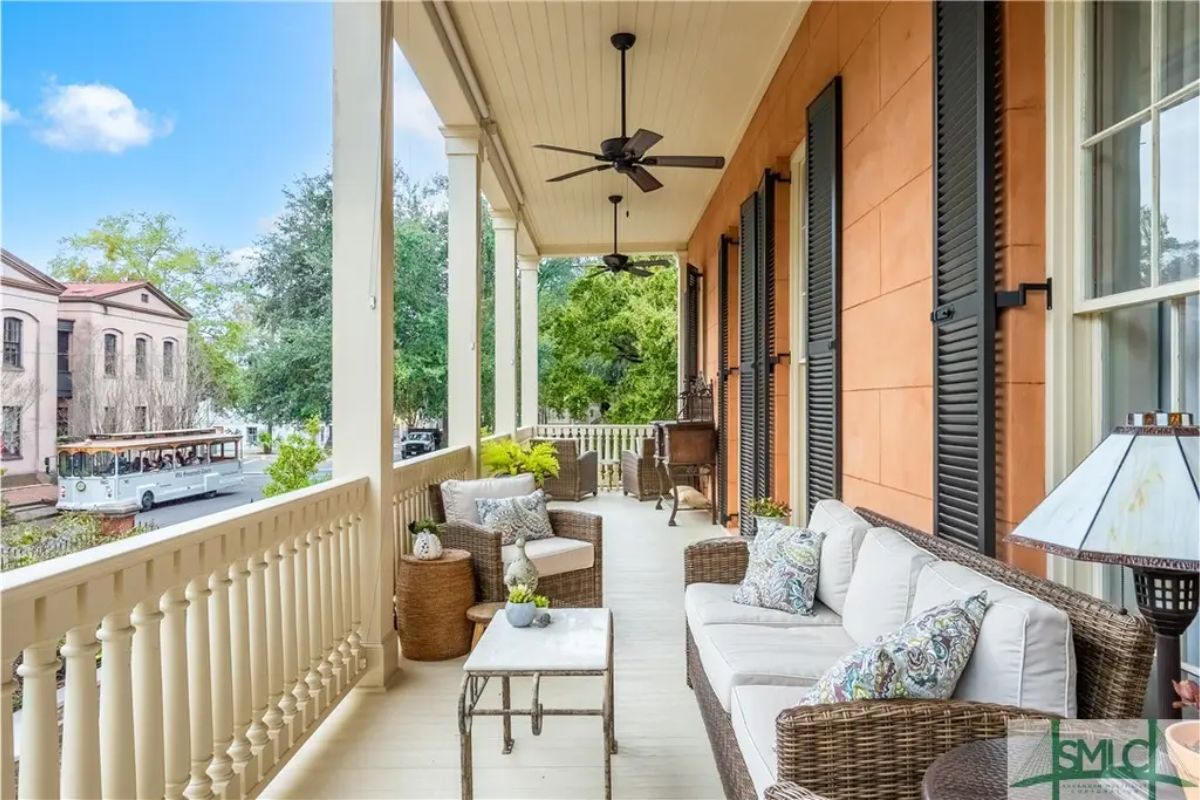 Long covered porch with white railing and ceiling fans for added comfort.