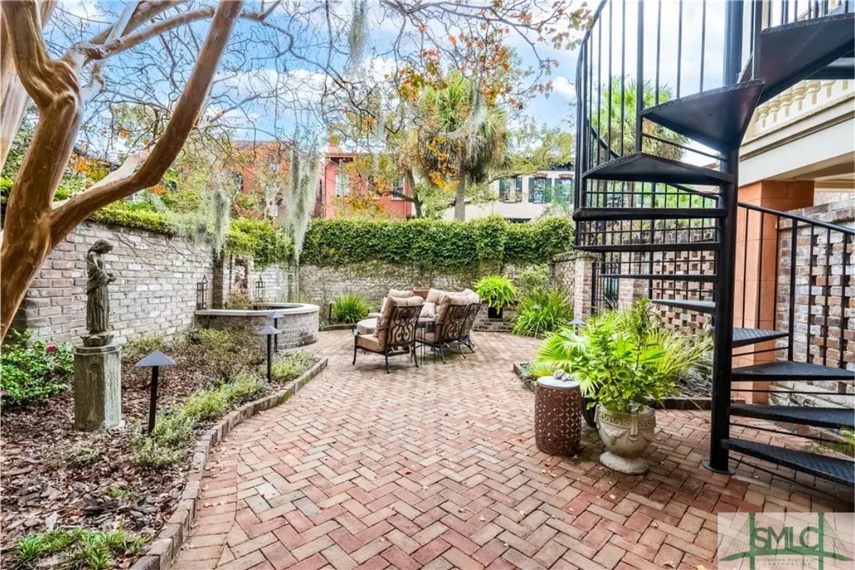 Outdoor courtyard paved with brick and surrounded by ivy-covered walls.