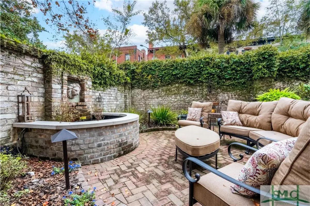 Circular brick courtyard surrounded by a high ivy-covered wall for privacy.