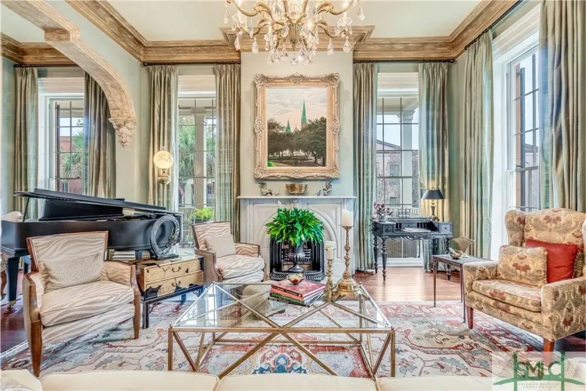 A grand piano anchors one corner of this light-filled room, framed by tall windows with draped curtains.