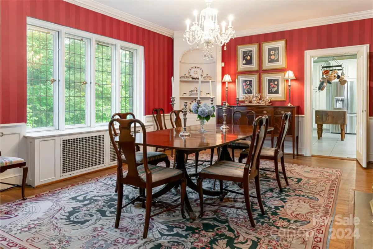 Dining room is accented with red striped wallpaper and wainscoting for a classic aesthetic.