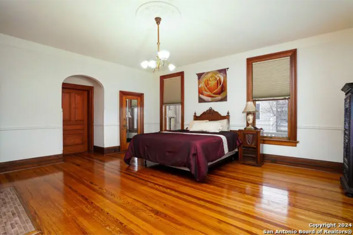 Large bedroom with gleaming hardwood floors and wood-framed windows.